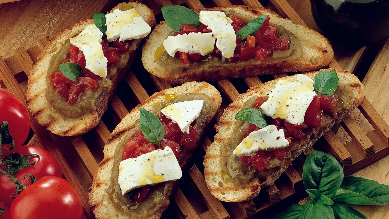 Bruschetta supersano con melanzane, pomodori e mozzarella fresca, guarnita con basilico e un filo d'olio.