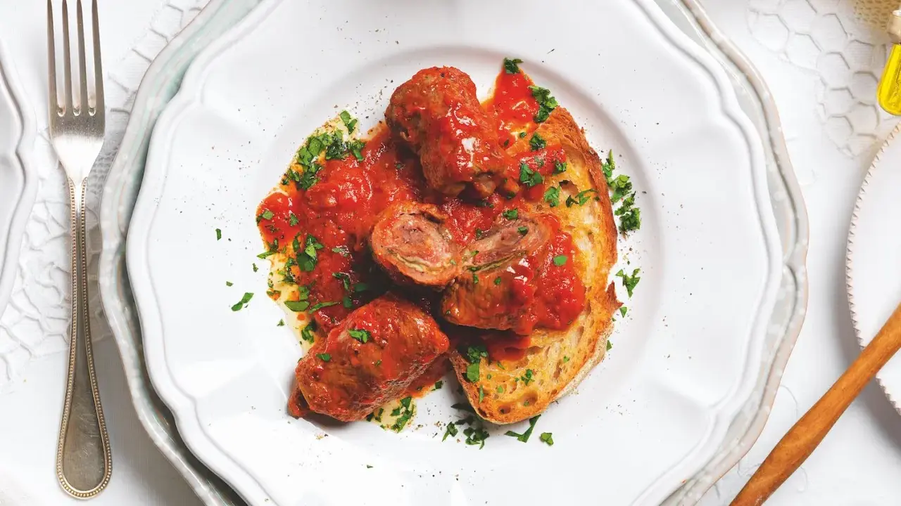 Braciole pugliesi in bianco, involtini di carne ripieni e cotti nel sugo, serviti su pane tostato e guarniti con prezzemolo fresco.