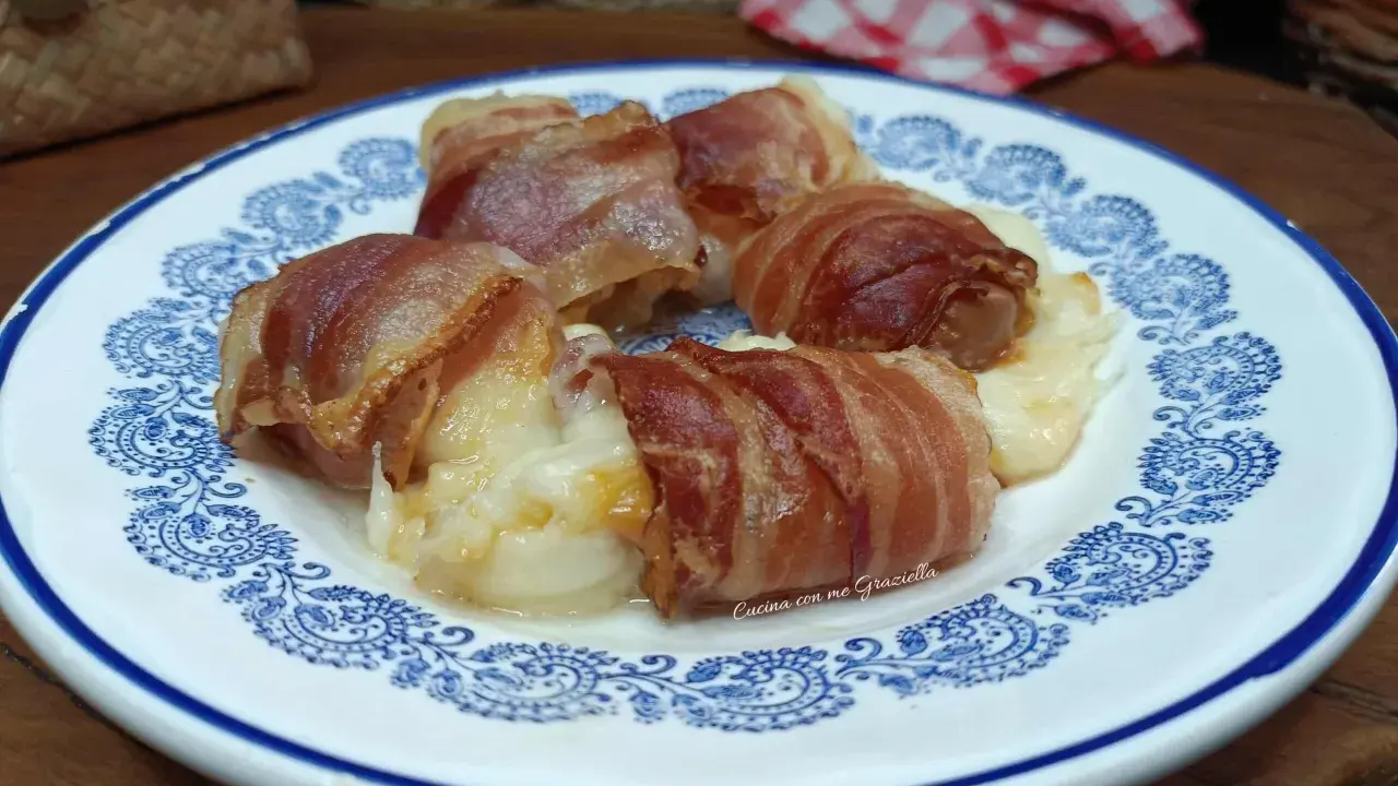 Involtini di interiora pugliesi avvolti in pancetta croccante, serviti su un piatto bianco con decorazioni blu.