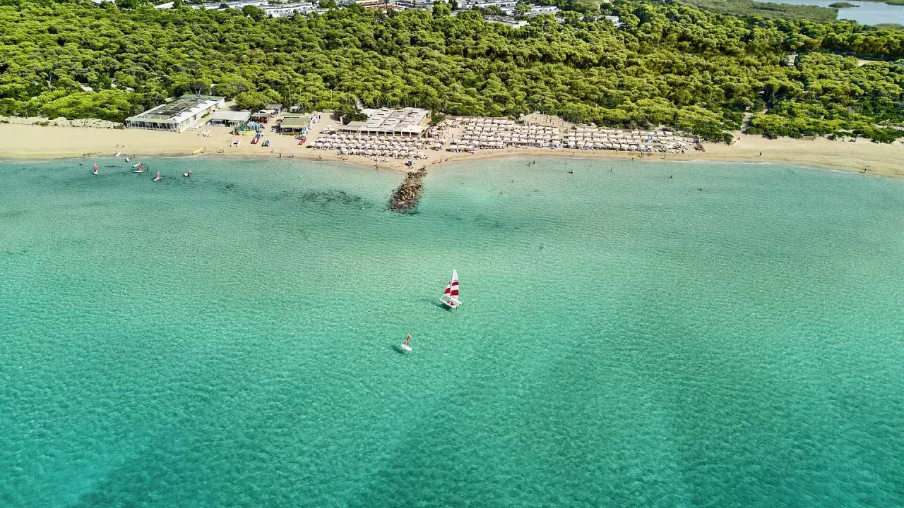 Spiaggia affollata con ombrelloni e mare cristallino a Marina di Ugento, dove si trova questo paradiso.