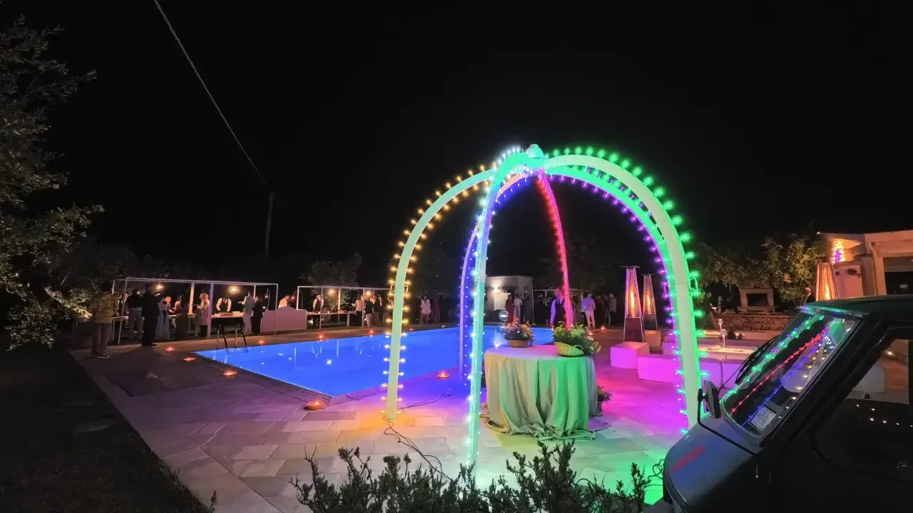 Serata magica con luci colorate, piscina illuminata e un'atmosfera da sagre di paese.