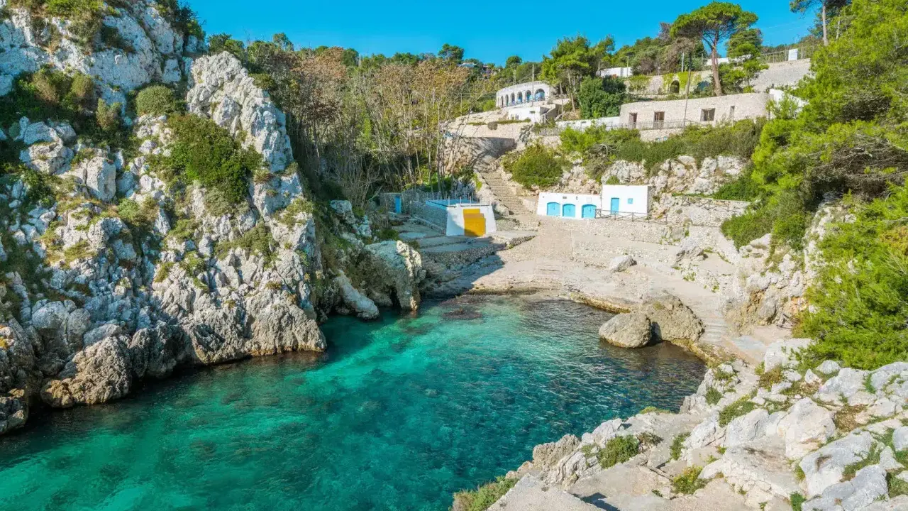Baia incantevole con acque cristalline, perfetta per un tour Puglia 10 giorni. Case bianche e rocce a picco sul mare.