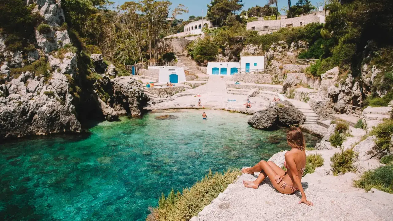 Una ragazza ammira la baia cristallina. Perfetto per decidere cosa fare stasera in Puglia: un tuffo rinfrescante!