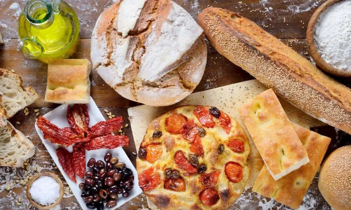 Pane, focaccia, pomodori secchi e olive: un assaggio dei piatti tipici pugliesi, con olio d'oliva e sale.