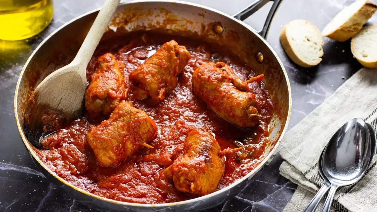 Braciola pugliese in padella con sugo rosso, pronte per essere gustate con pane fresco.