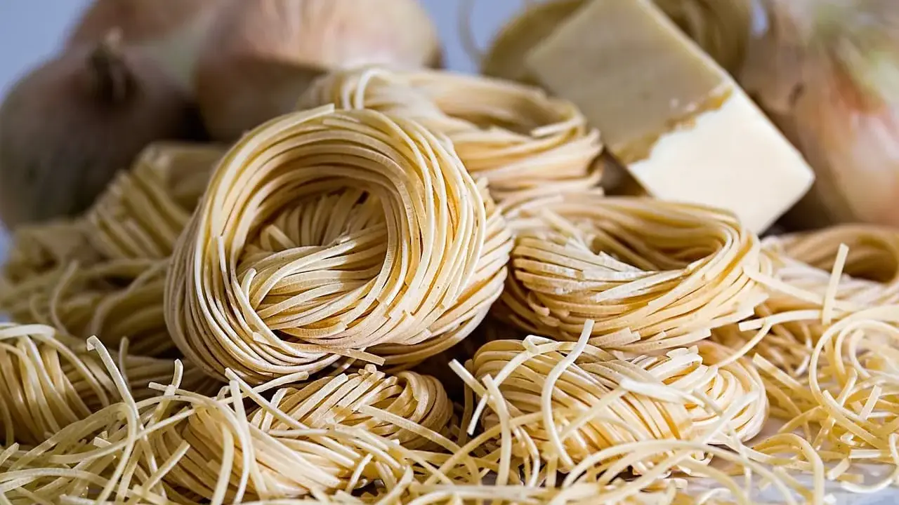 Nidi di pasta fresca, cipolle e un pezzo di formaggio, ingredienti perfetti per gustosi contorni pugliesi.