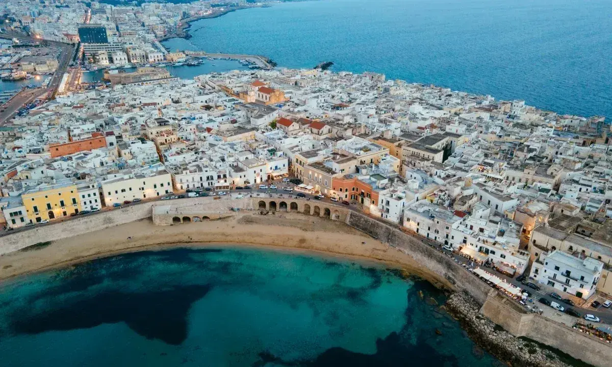Vista aerea di Gallipoli, con le sue case bianche affacciate sul mare turchese. Immagina le feste estive e la vivacità di questa perla salentina.