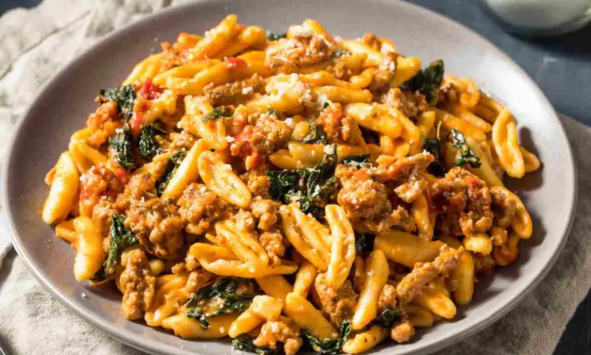 Un piatto di pasta con salsiccia sbriciolata, verdure e formaggio grattugiato, un sapore autentico dei primi piatti foggiani.