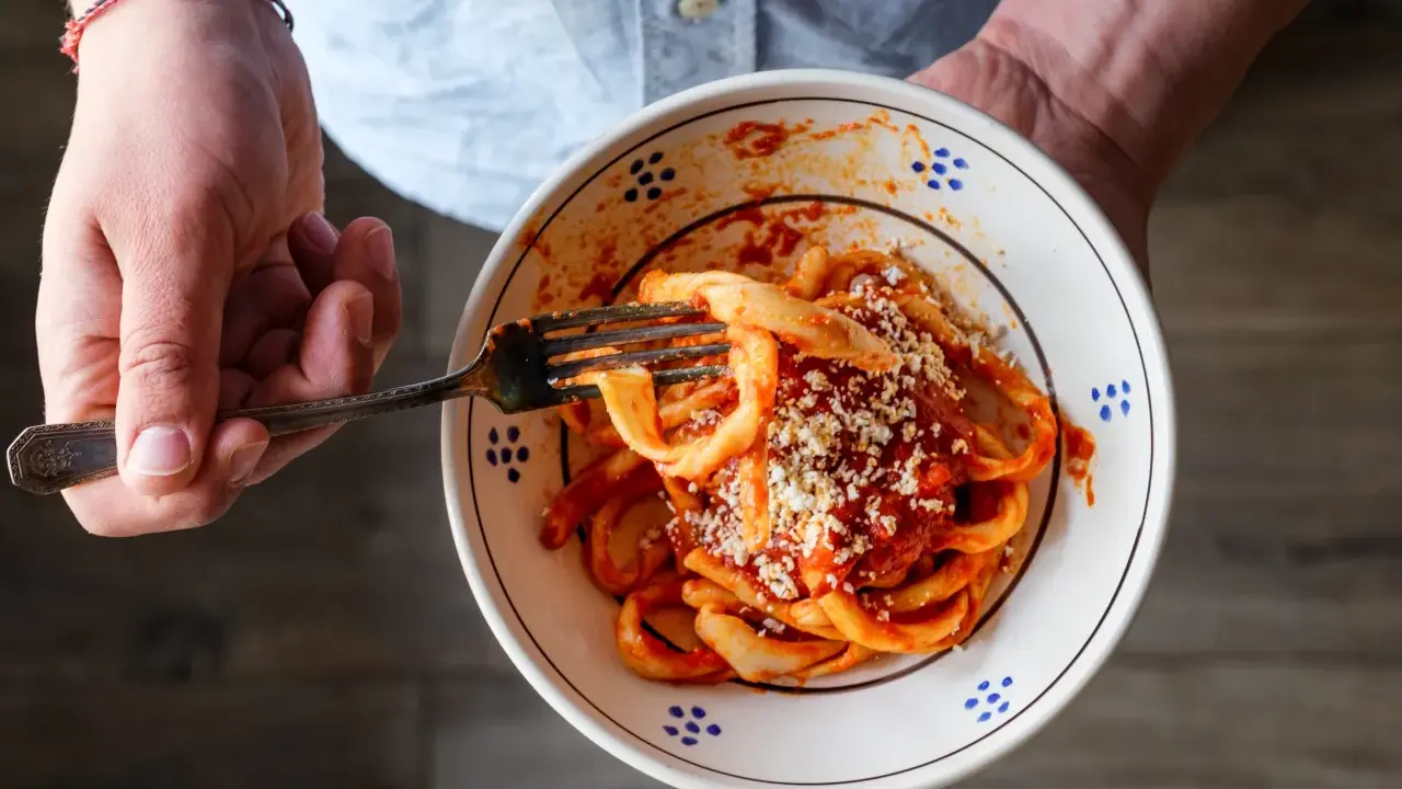Un piatto di sagne al ragù, condite con formaggio grattugiato, pronto per essere gustato.