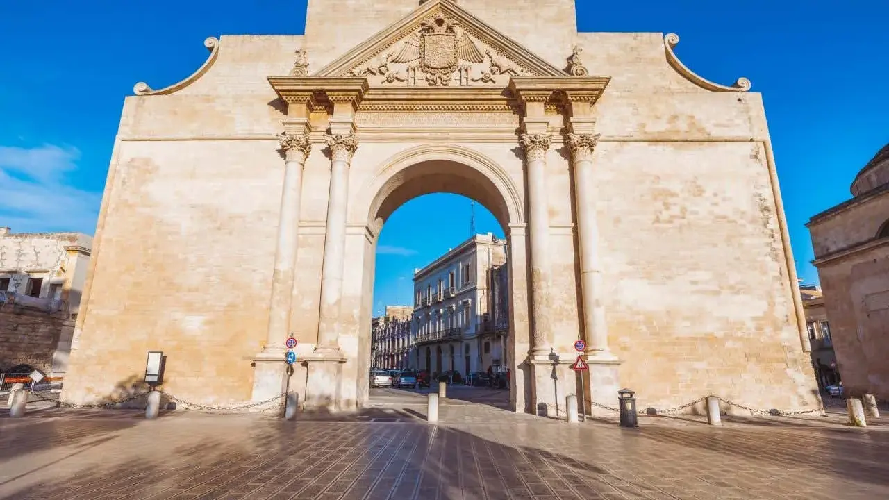 Porta Napoli, un arco trionfale in pietra leccese, invita a scoprire le cose da fare a Lecce. Un'antica porta che segna l'ingresso alla città barocca.