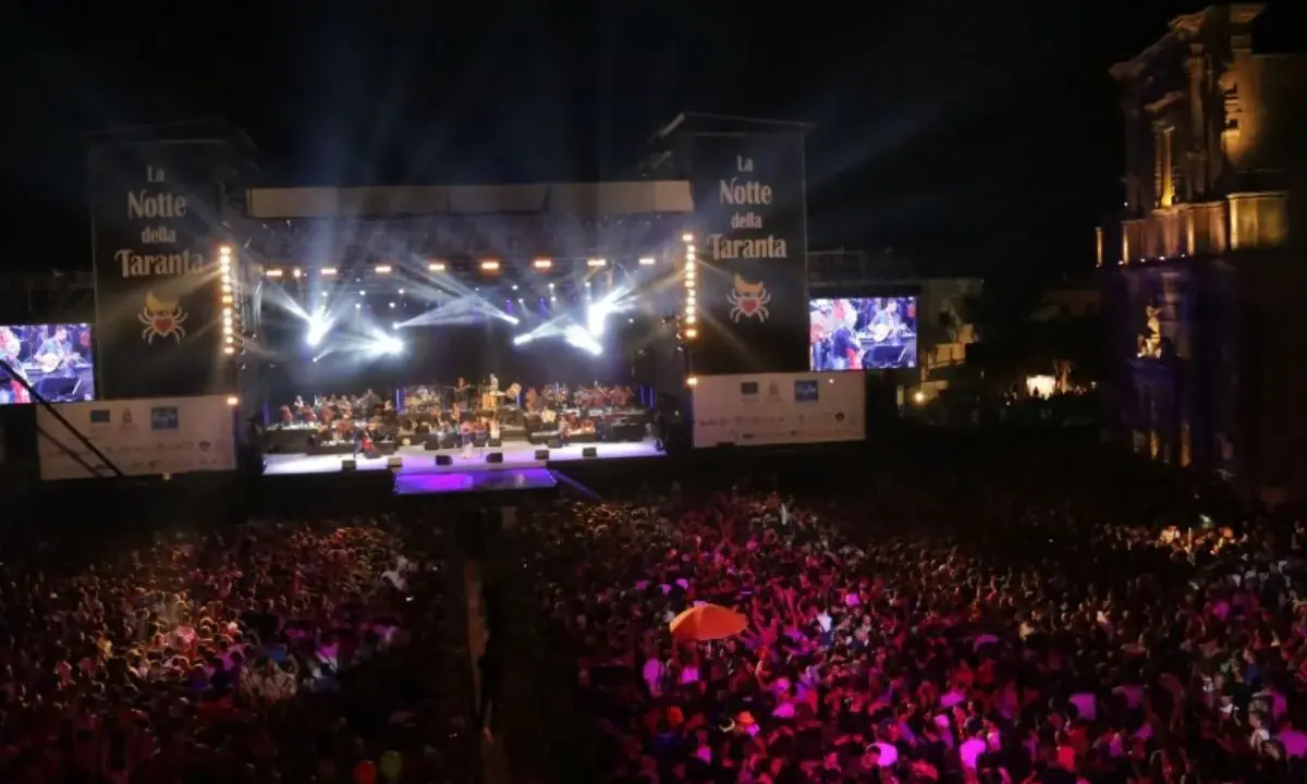 La Notte della Taranta, un'enorme folla festeggia sotto un palco illuminato. Le feste di settembre in Puglia sono magiche!