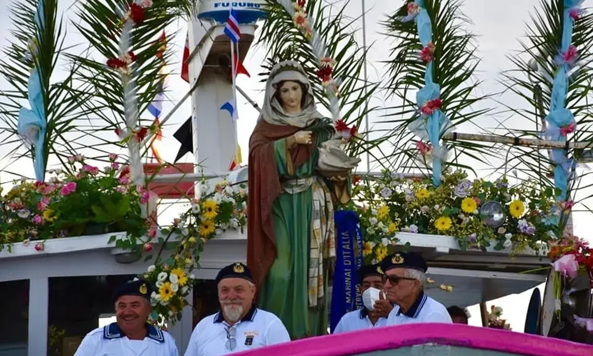 Statua della Madonna su un peschereccio addobbato per la festa patronale di Santa Cesarea Terme, con marinai sorridenti.