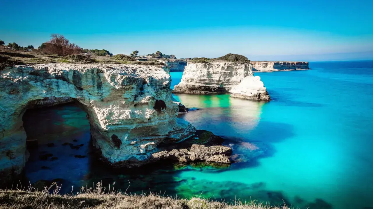 Scogliere bianche e mare turchese, un sogno per i mete puglia estate. L'arco naturale invita a scoprire le acque cristalline.