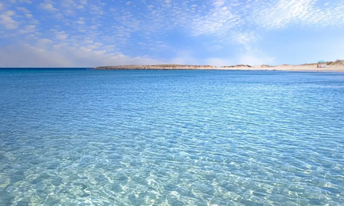 Acque cristalline e cielo azzurro con nuvole leggere, un invito a rilassarsi in questo splendido lido marini.