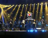 Artisti sul palco con tamburelli, orchestra e luci scintillanti per la sagra della taranta.