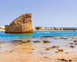La torre pali di Lido Marini, con il mare cristallino e le case bianche sullo sfondo, evoca un'estate senza fine.