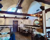 Interno accogliente con tavoli apparecchiati, travi in legno e luci soffuse. Un luogo dove scoprire i sapori nostri Sternatia.