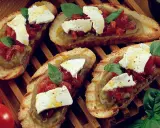 Bruschetta supersano con melanzane, pomodori e mozzarella fresca, guarnita con basilico e un filo d'olio.
