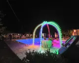 Serata magica con luci colorate, piscina illuminata e un'atmosfera da sagre di paese.
