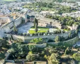 Castello normanno con torri rotonde e mura merlate, ideale per scoprire dove andare a Pasquetta in Puglia, circondato da verde e un borgo.