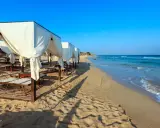 Spiaggia di Pescoluse con gazebo bianchi e lettini, mare azzurro e sabbia dorata. Ecco cosa vedere a Pescoluse per una vacanza da sogno.
