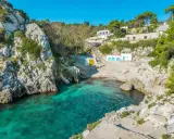 Baia incantevole con acque cristalline, perfetta per un tour Puglia 10 giorni. Case bianche e rocce a picco sul mare.