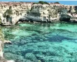 Scogliere bianche e acque cristalline, un paradiso tra le spiagge Puglia. Nuotatori si godono il mare turchese.