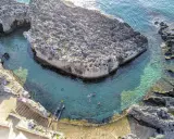 Tricase cosa vedere: una baia rocciosa con acque cristalline e persone che nuotano. Un luogo incantevole per godersi il mare.