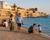 Famiglia passeggia sulla spiaggia di **Salento, Italia**, con un borgo storico sullo sfondo.