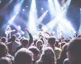 Folla entusiasta a un concerto in Puglia il 1 maggio, con luci intense e musicisti sul palco.