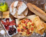 Pane, focaccia, pomodori secchi e olive: un assaggio dei piatti tipici pugliesi, con olio d'oliva e sale.
