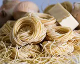 Nidi di pasta fresca, cipolle e un pezzo di formaggio, ingredienti perfetti per gustosi contorni pugliesi.