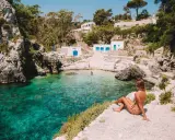 Una donna ammira il mare cristallino di una caletta pugliese. Perfetto per capire quando andare in Puglia per una vacanza indimenticabile.