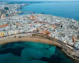 Vista aerea di Gallipoli, con le sue case bianche affacciate sul mare turchese. Immagina le feste estive e la vivacità di questa perla salentina.