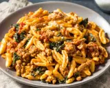 Un piatto di pasta con salsiccia sbriciolata, verdure e formaggio grattugiato, un sapore autentico dei primi piatti foggiani.
