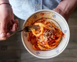 Un piatto di sagne al ragù, condite con formaggio grattugiato, pronto per essere gustato.