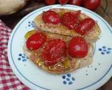 Pane e pomodoro, un assaggio dei campi salentini. Bruschette condite con pomodorini freschi, olio d'oliva e origano, su un piatto decorato.