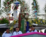Statua della Madonna su un peschereccio addobbato per la festa patronale di Santa Cesarea Terme, con marinai sorridenti.
