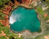 Laguna turchese in un cratere dalle rocce rosse, un paesaggio surreale delle cave di bauxite Otranto.