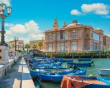 Barche blu ormeggiate nel porto di Bari, con il Teatro Margherita sullo sfondo. Un'immagine che cattura l'essenza di cosa vedere a Bari.