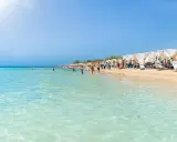 Spiaggia pugliese con acque cristalline e lettini sotto gazebo bianchi, ideale località mare Puglia per famiglie.