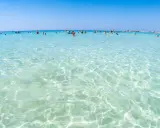 Acque cristalline e turchesi bagnano le spiagge di Lecce, dove bagnanti si godono il sole e il mare limpido.