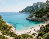 Sentiero panoramico verso una delle splendide calette del Salento, con acqua cristallina e rocce imponenti.