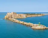 Fortezza Aragonese e faro verde a Brindisi, dove il mare azzurro incontra la storia.