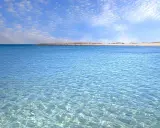 Acque cristalline e cielo azzurro con nuvole leggere, un invito a rilassarsi in questo splendido lido marini.