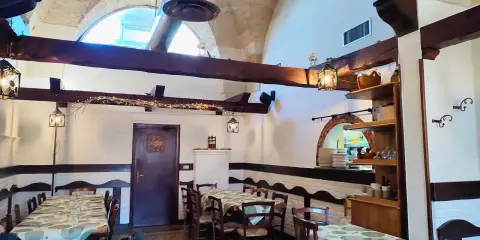 Interno accogliente con tavoli apparecchiati, travi in legno e luci soffuse. Un luogo dove scoprire i sapori nostri Sternatia.