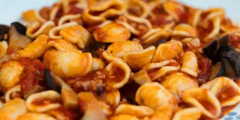 Orecchiette alla tarantina con melanzane e pomodoro, un piatto ricco e saporito.