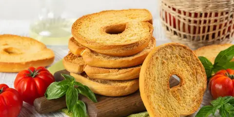 Fette dorate di pane tipico pugliese, con pomodori freschi e basilico, pronte per essere gustate.