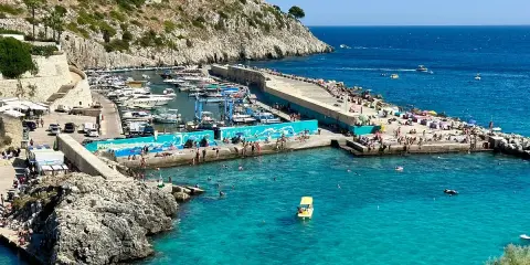 Un'estate a Castro: gente in spiaggia, barche nel porto e acque cristalline. Perfetto per scoprire cosa fare a Castro.