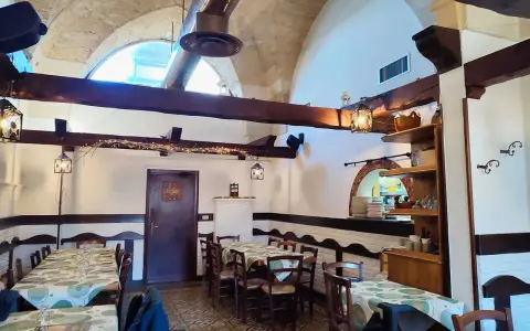 Interno accogliente con tavoli apparecchiati, travi in legno e luci soffuse. Un luogo dove scoprire i sapori nostri Sternatia.
